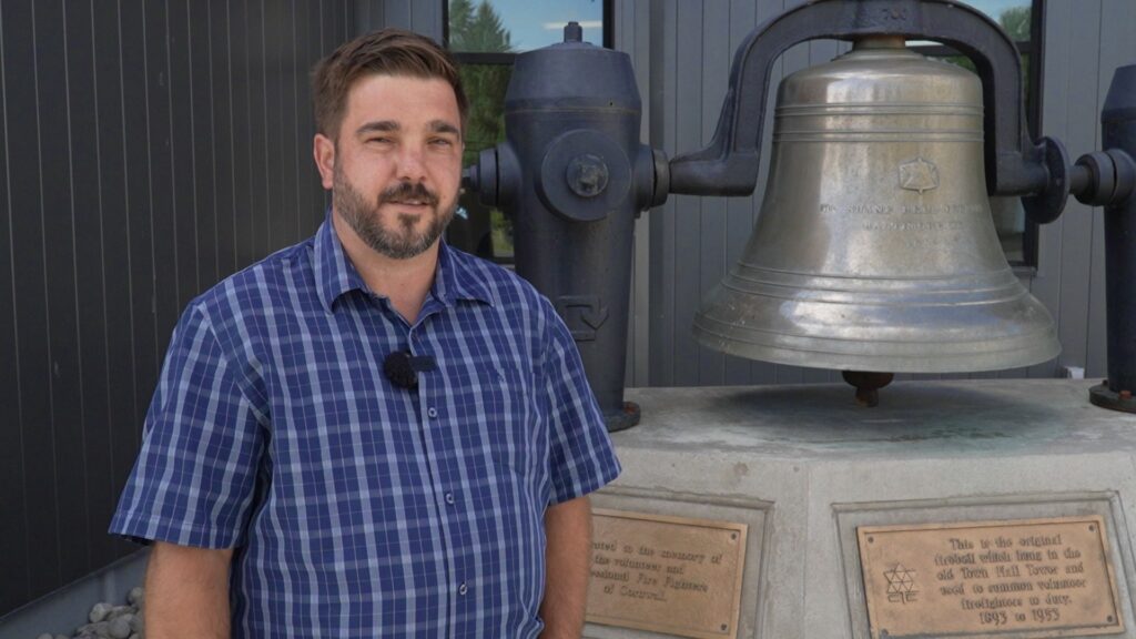 Brent Whitford à côté de l'ancienne cloche d'alarme de la caserne de pompier