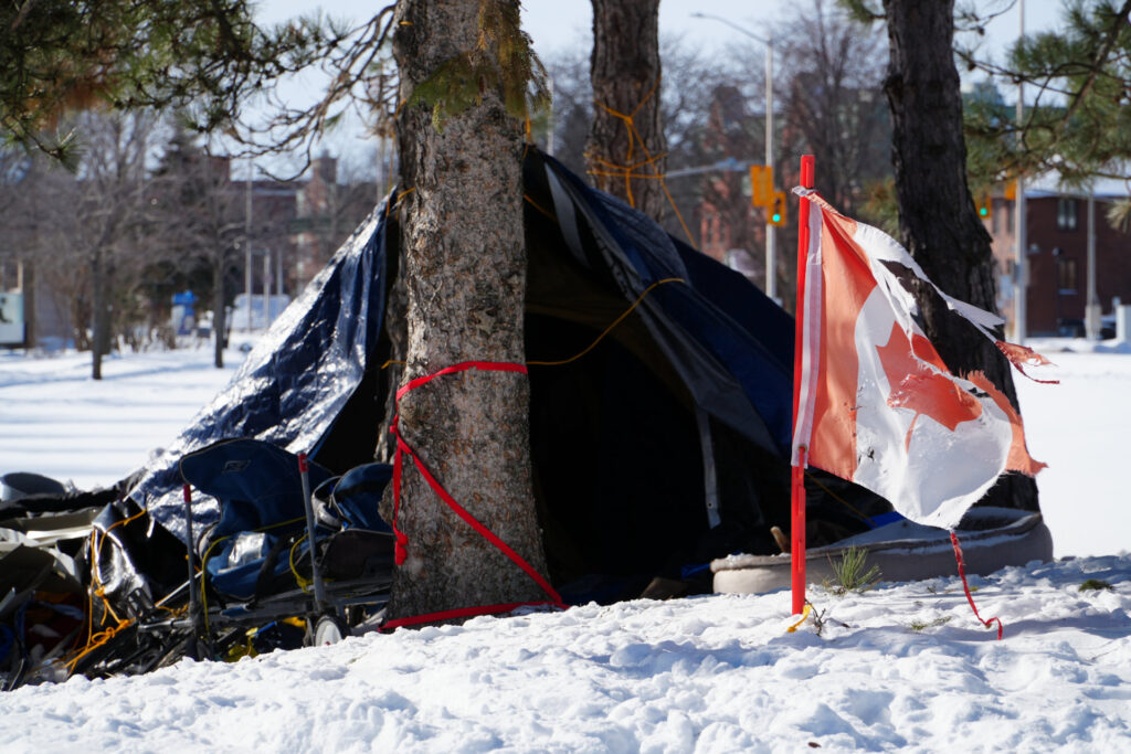 Drapeau canadien déchiré qui flotte devant la tente d'un sans abri dans la neige à Cornwall