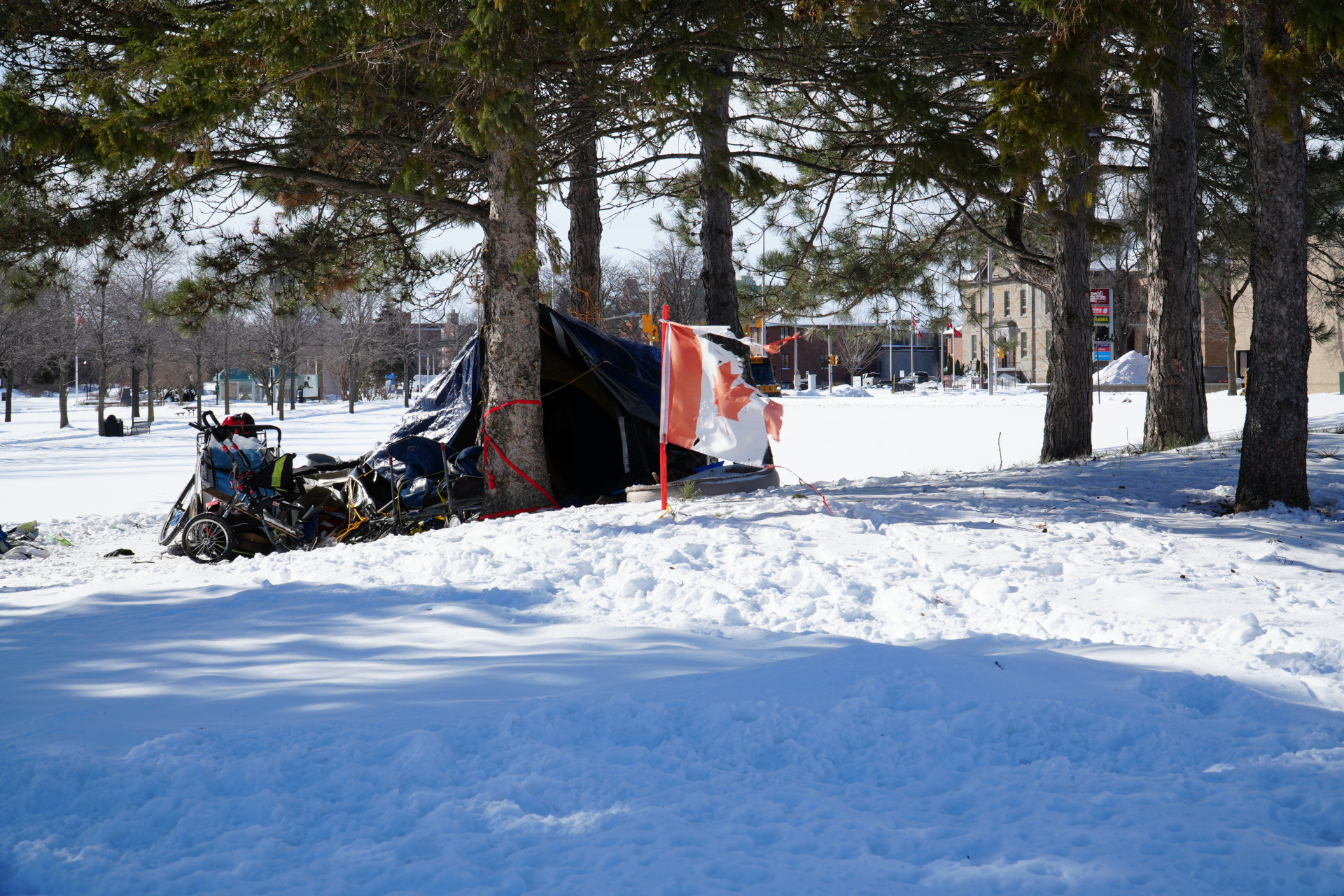 Drapeau canadien déchiré qui flotte devant la tente d'un sans abri dans la neige à Cornwall