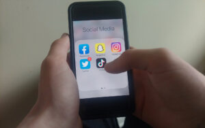 Jeunes qui tient un cellulaire dans les main avec un menu de média sociaux