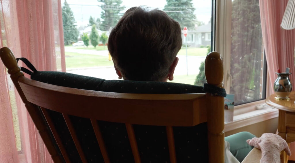 Personne âgée vue de dos assise sur une chaise à bascule
