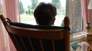 Personne âgée vue de dos assise sur une chaise à bascule