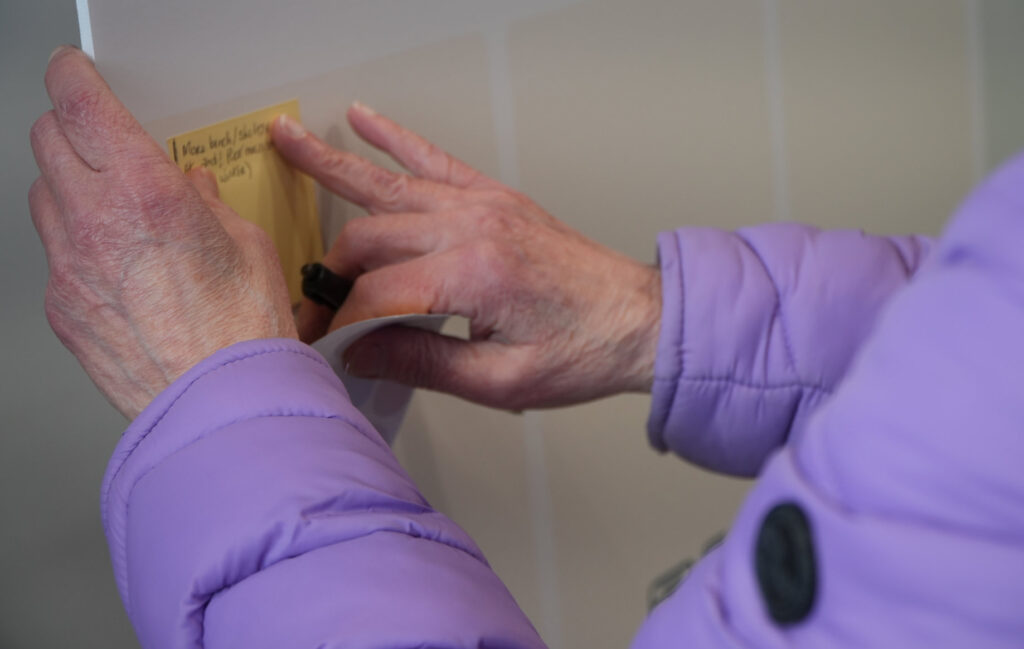 Main d'une personne âgée qui colle un post-it