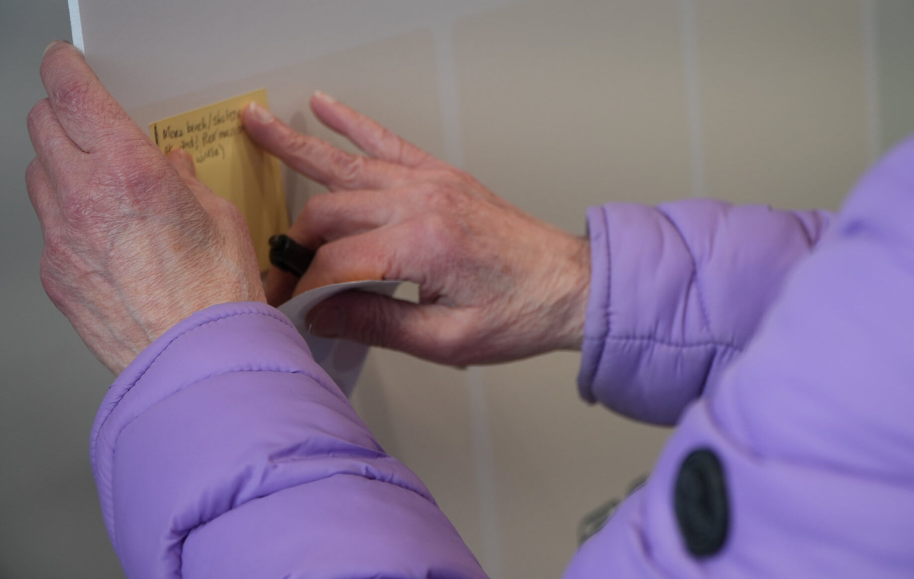 Main d'une personne âgée qui colle un post-it