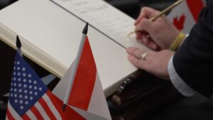 drapeau américain et canadien avec en fond une main qui signe un accord