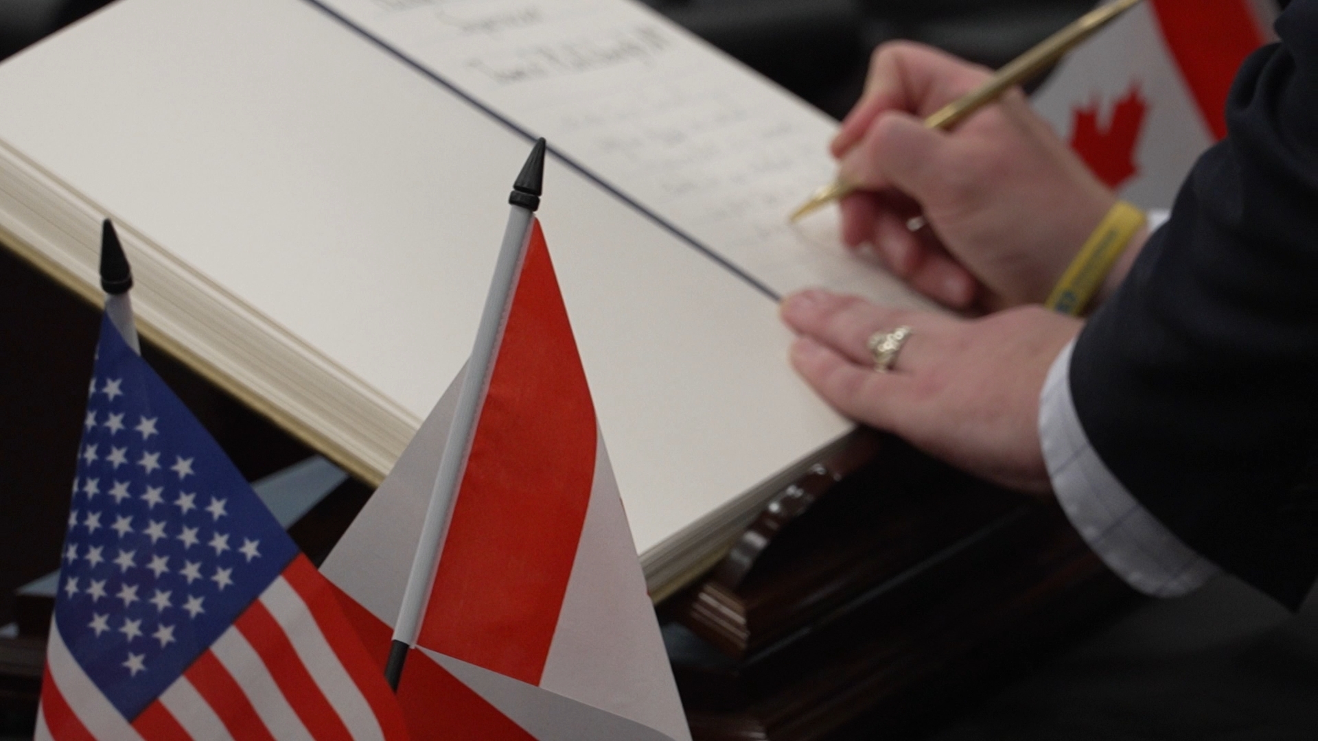 drapeau américain et canadien avec en fond une main qui signe un accord