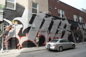 Mur avec un graffiti sur plusieurs façades dans une rue
