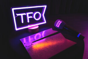 Logo lumineux de TFO avec un micro et un clap