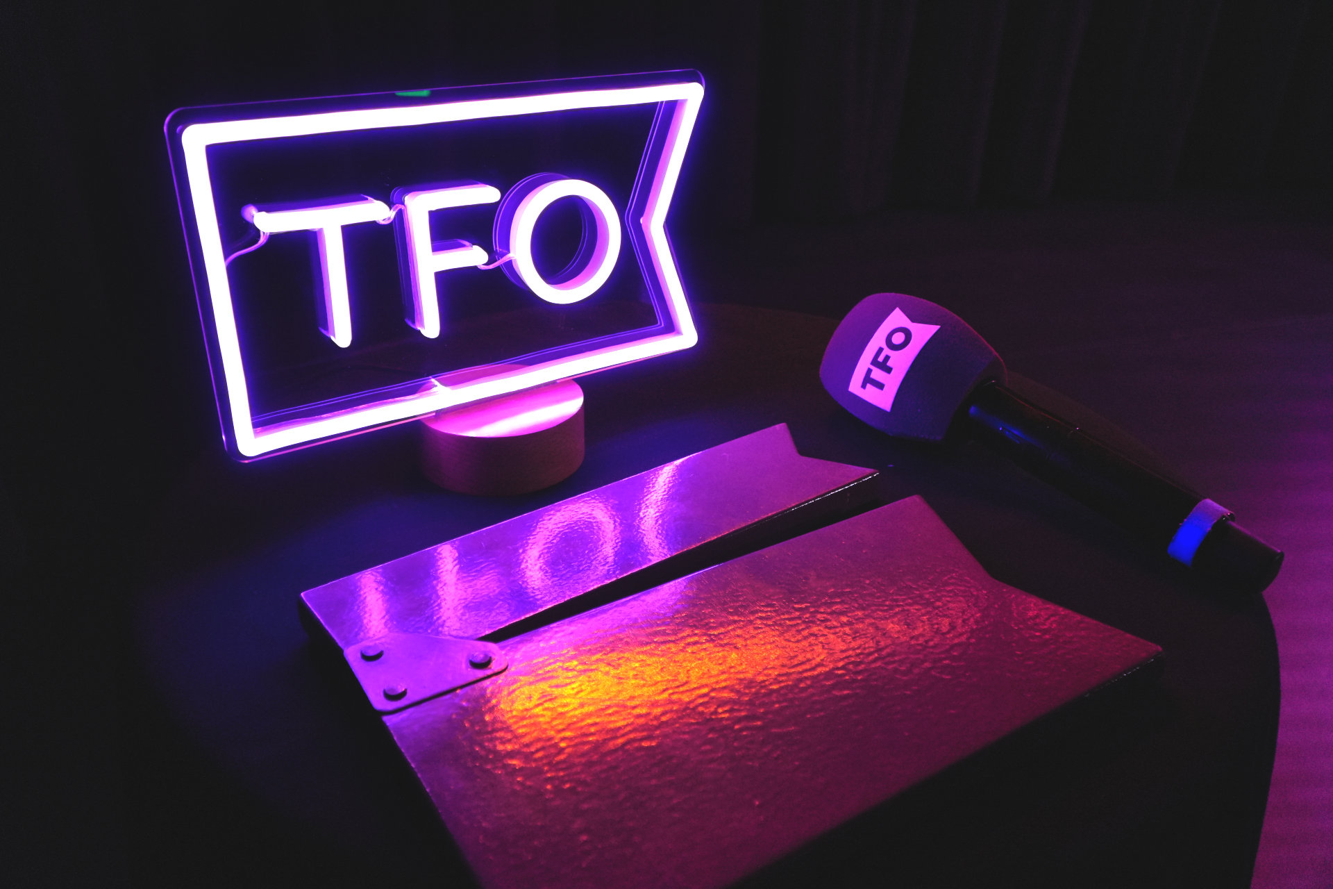Logo lumineux de TFO avec un micro et un clap
